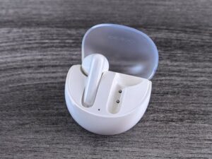 Stylish white wireless earbuds with a sleek case on a modern wooden background.